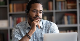 A man wears headphones and works on his computer. 